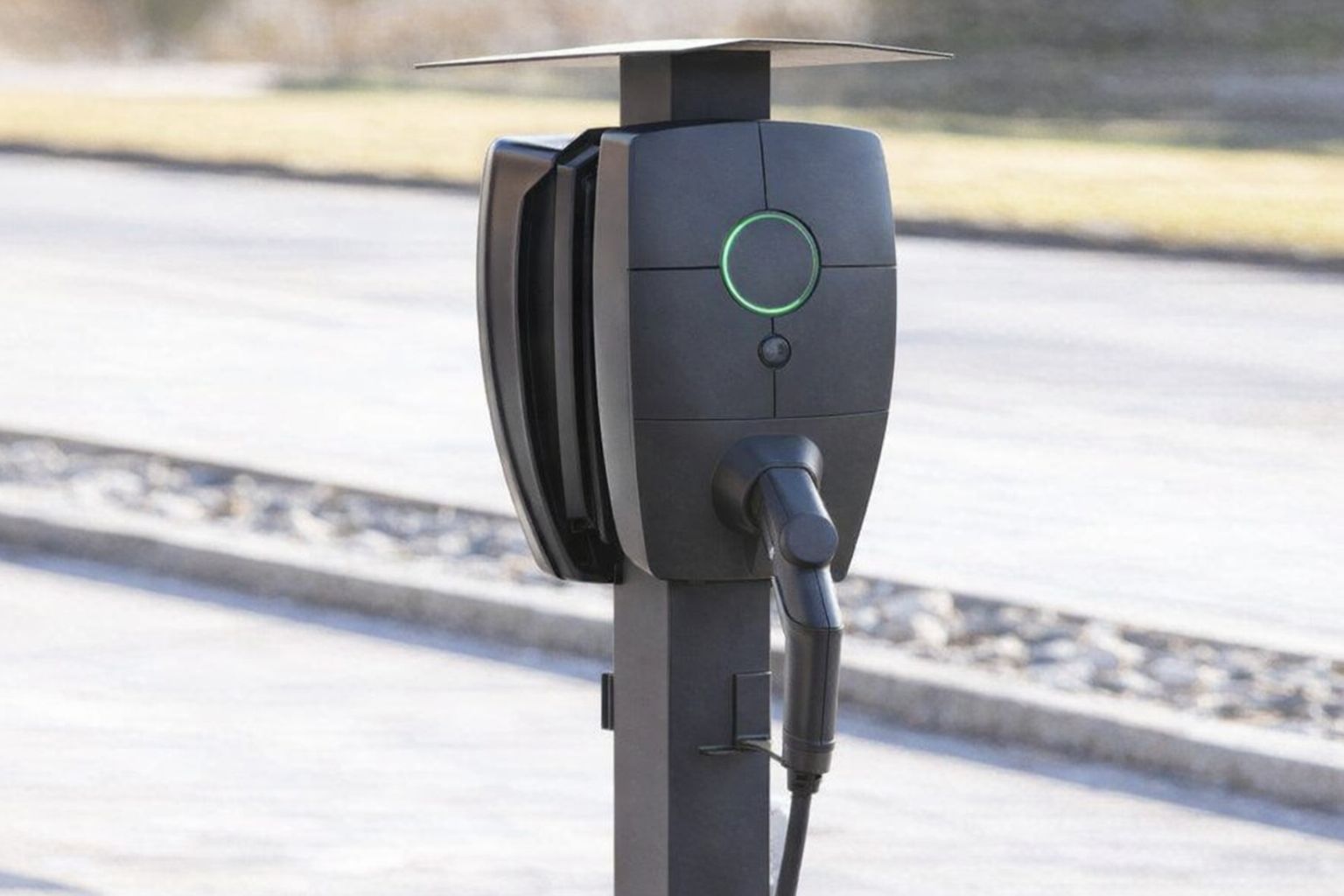 En svart Zaptec Pro laddbox installerad på en stolpe utomhus.